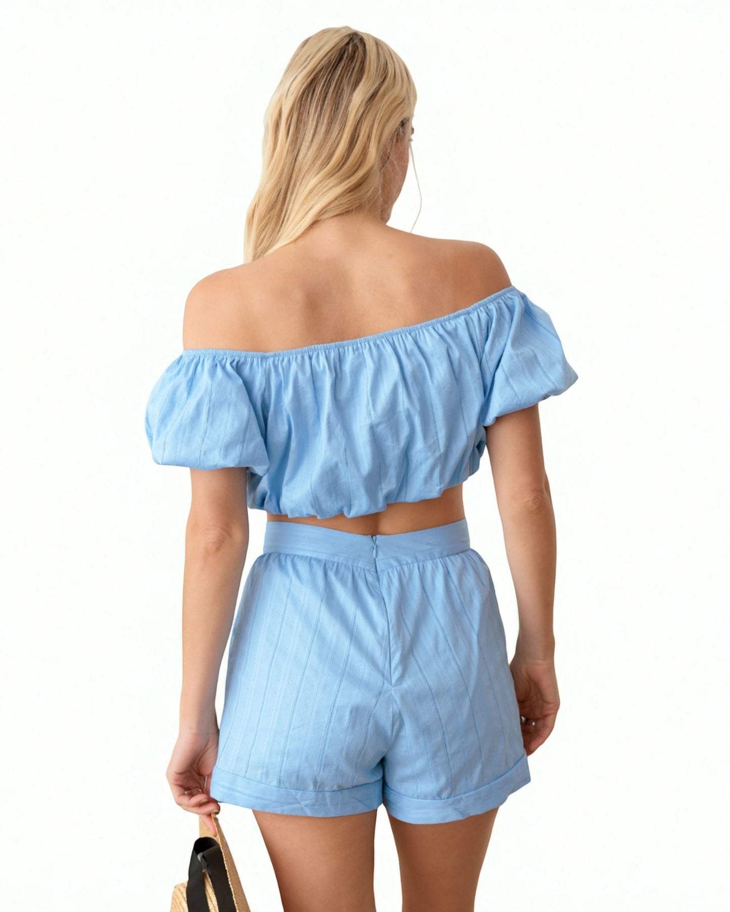 Woman wearing a light blue off-shoulder top and shorts set on a white background