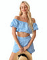 Woman wearing a light blue off-shoulder top and shorts set on a white background