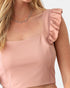 A close-up of a woman wearing a dusty pink ruffled crop top with a square neckline and a delicate silver necklace.