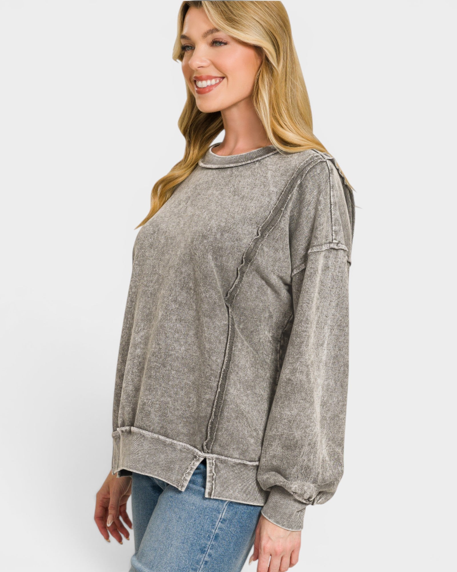 Woman wearing a gray sweatshirt and blue jeans on a white background