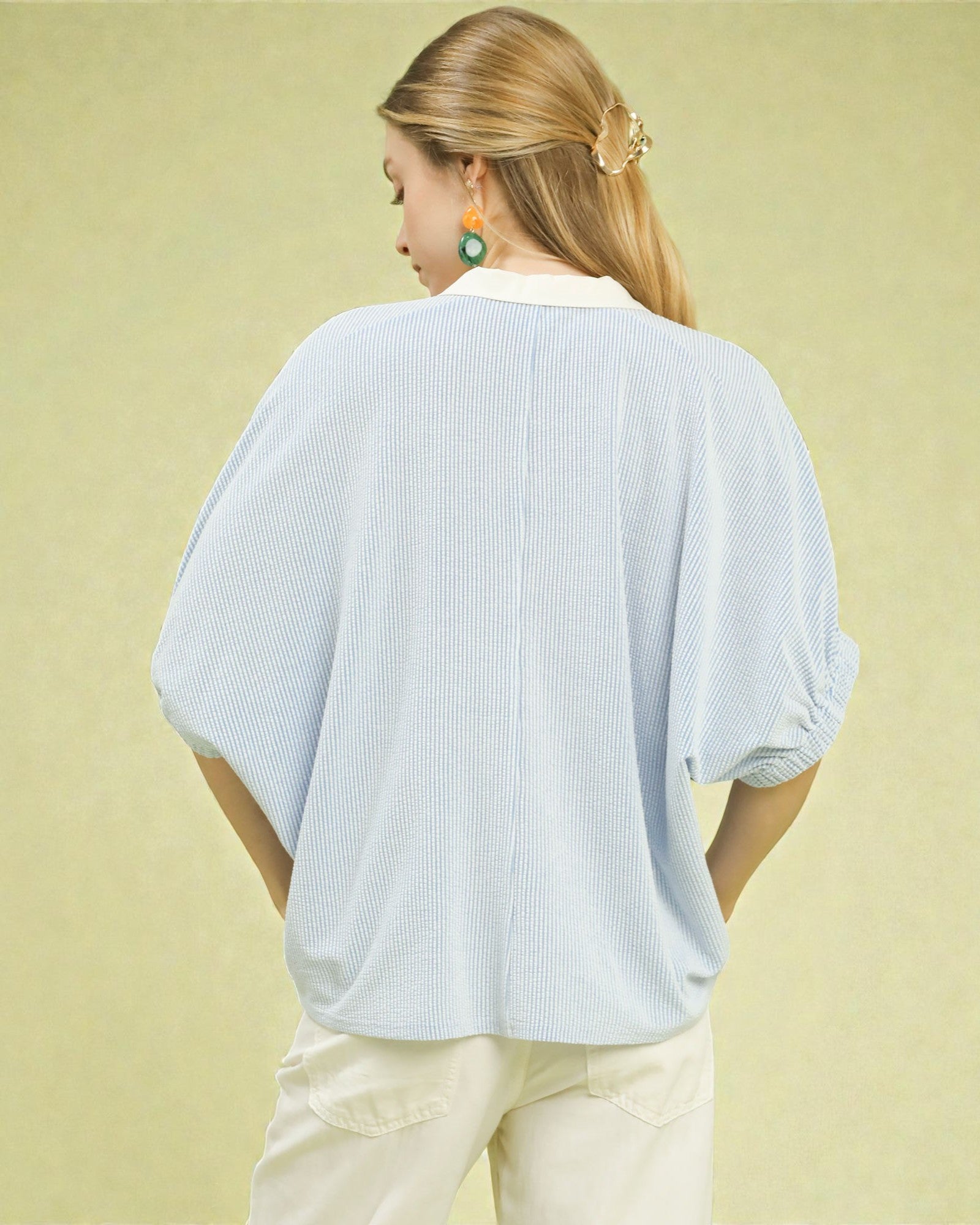 Woman wearing a light blue textured blouse against a yellow background