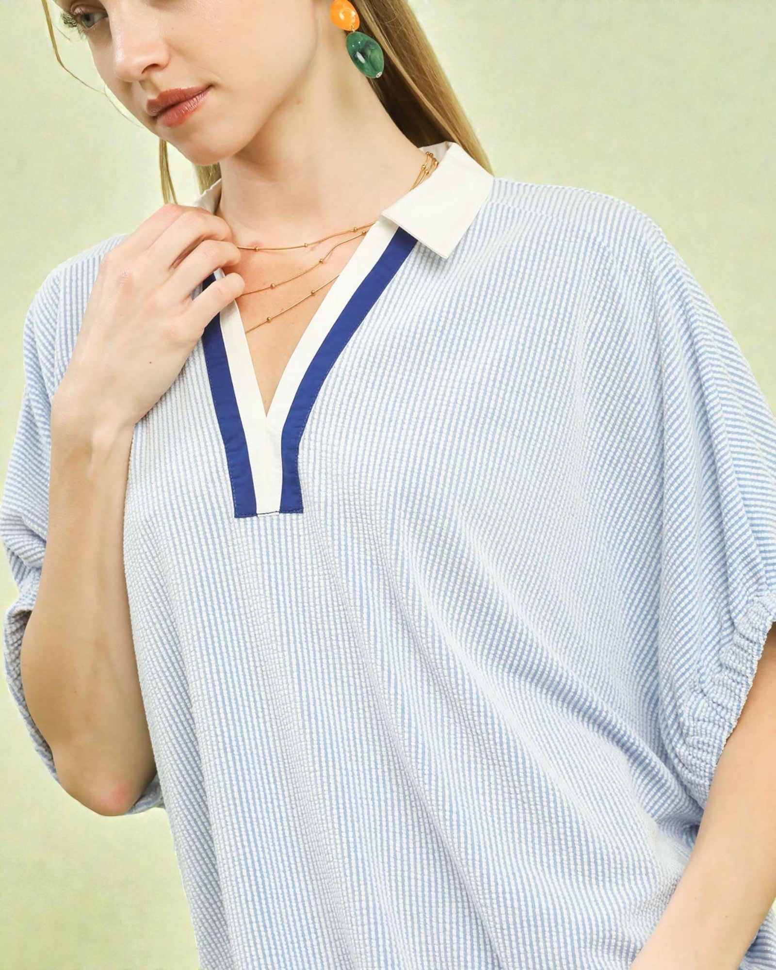 Woman wearing a blue and white striped shirt with a plain background