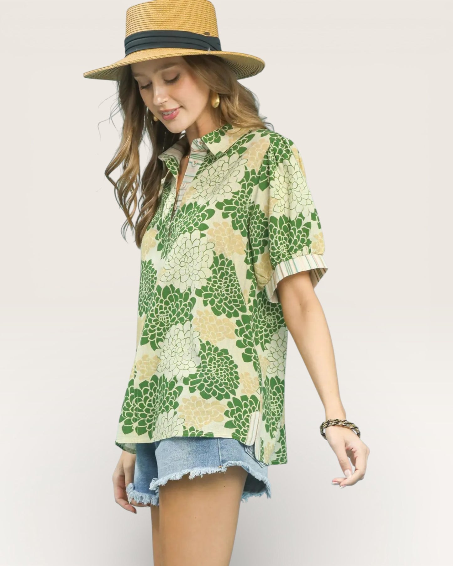 Woman wearing a green floral shirt and straw hat on a plain background