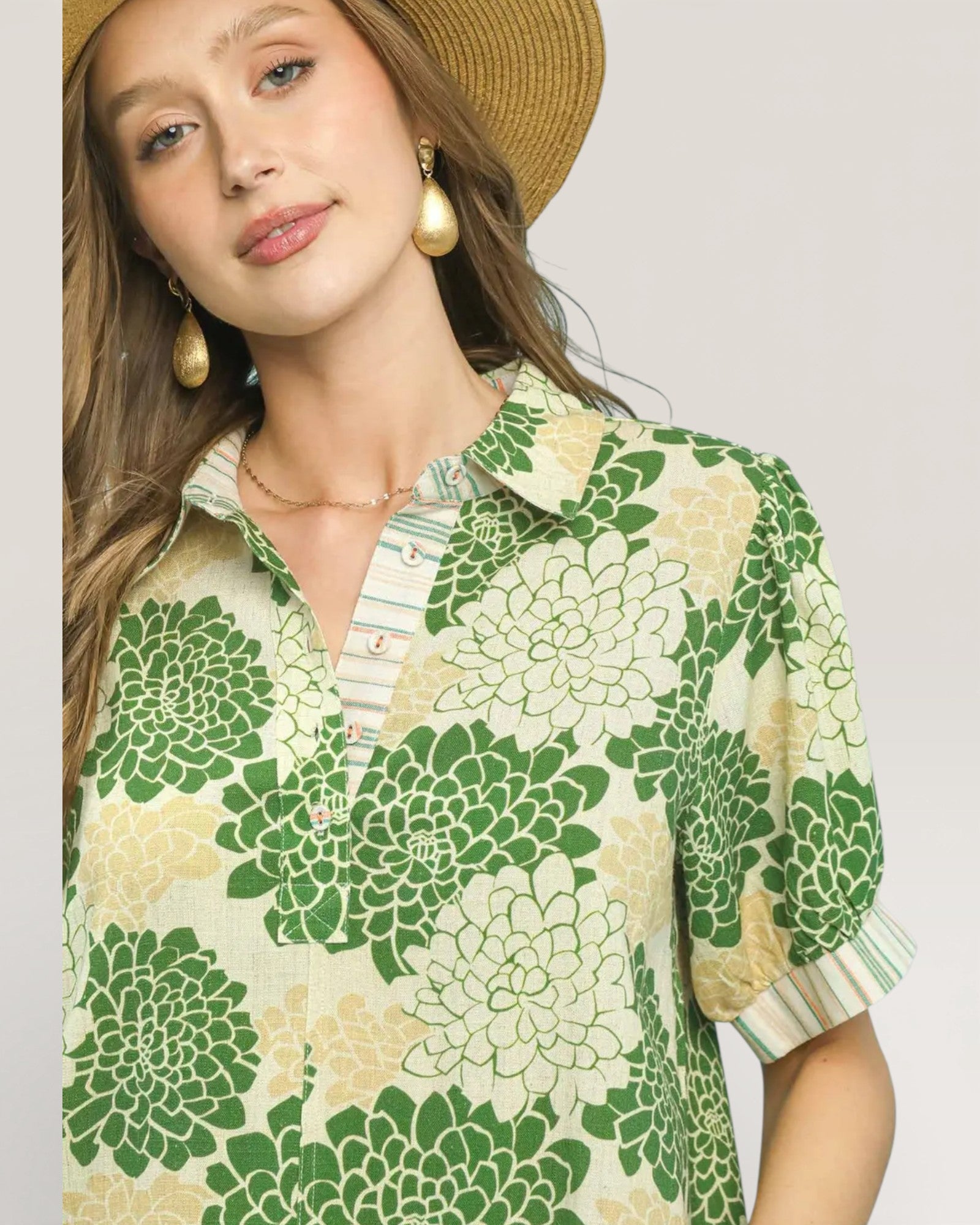Woman wearing a green and beige floral patterned shirt with a neutral background