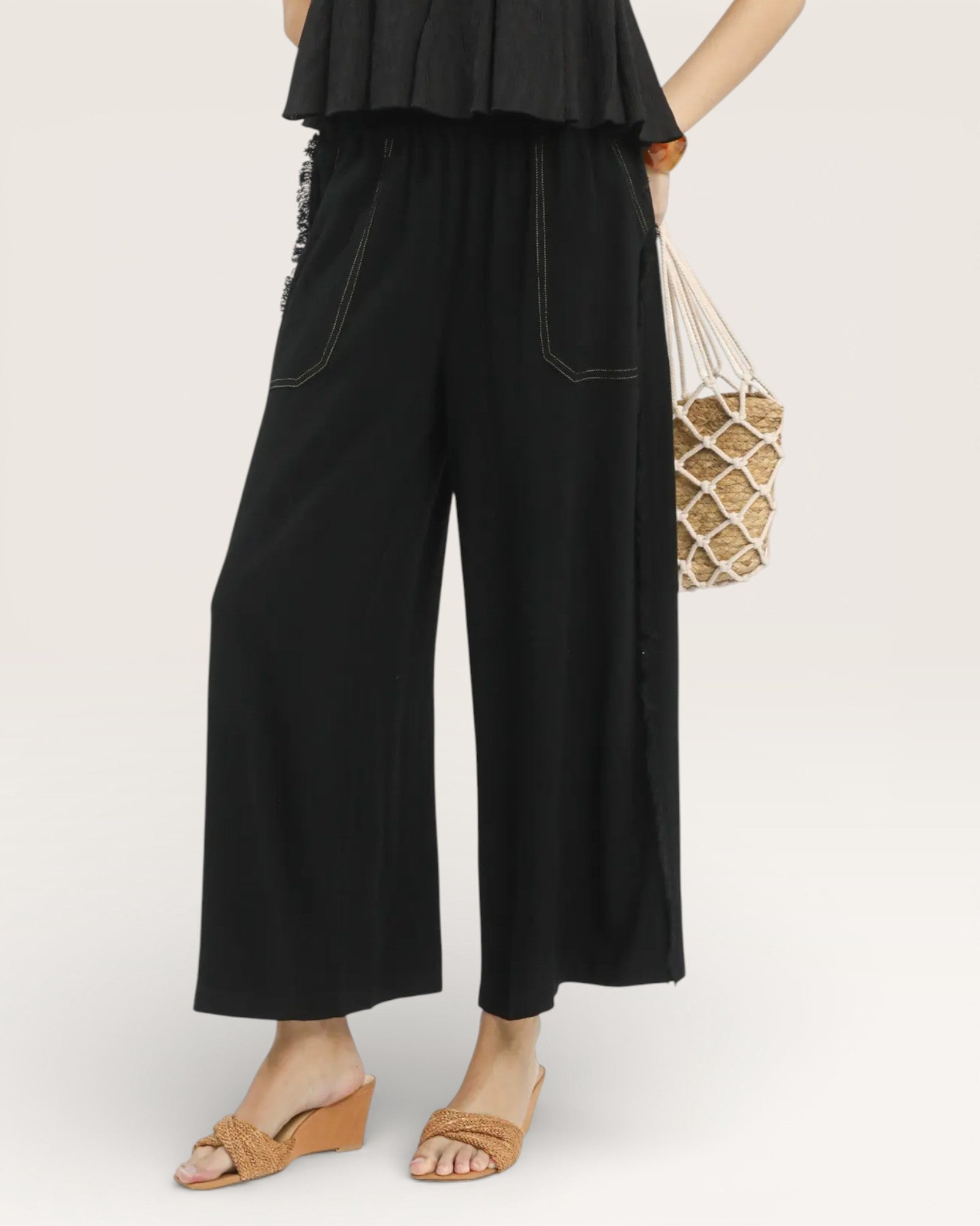 Person wearing black wide-leg pants with a plain background