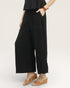 Person wearing black wide-leg pants and brown sandals on a white background