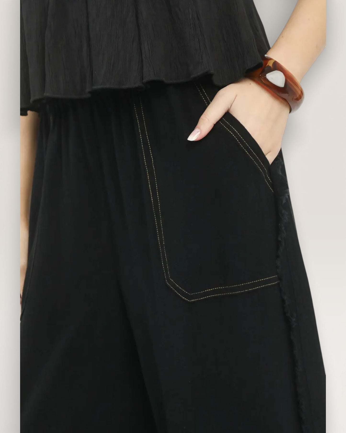 Person wearing black pants with a plain background