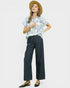 Woman wearing a patterned shirt and wide-leg pants with a straw hat on a white background