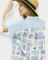 Woman wearing a striped shirt with a geometric patterned towel draped over her shoulder against a white background