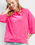 Woman wearing a bright pink textured top against a plain background
