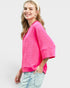 Woman wearing a bright pink lace top with light blue jeans on a white background