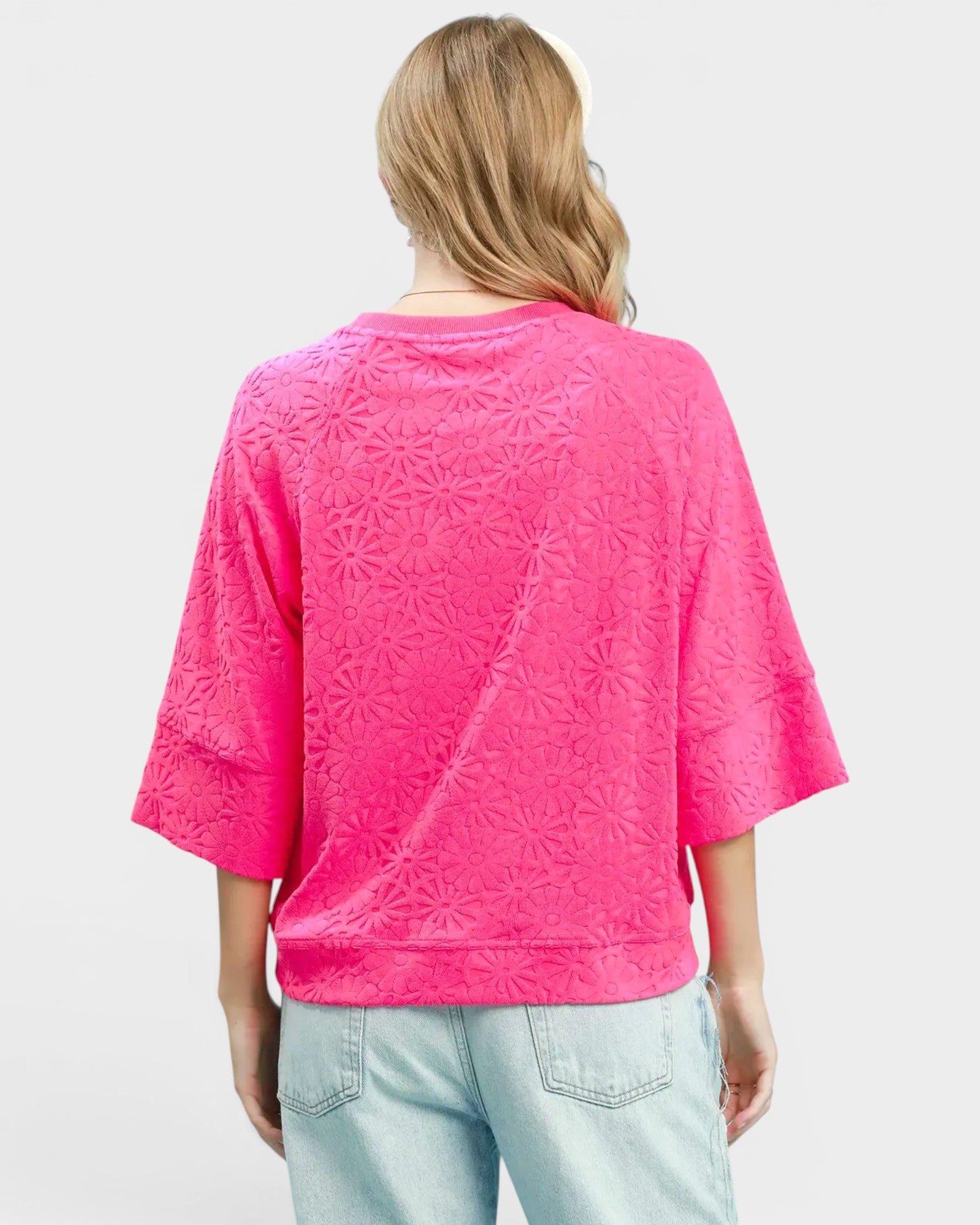 Person wearing a pink textured shirt and light blue jeans on a plain background