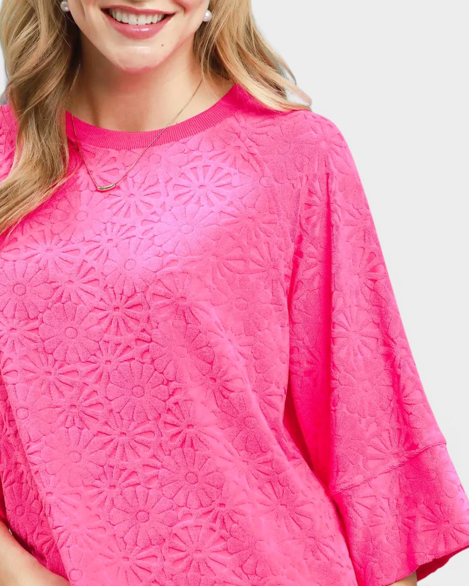 Close-up of a person wearing a bright pink textured top on a white background
