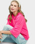 Woman wearing a bright pink sweater and light blue jeans on a white background