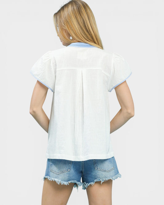Woman wearing a white denim shirt and denim shorts on a plain background