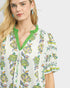 Woman wearing a floral blouse with green trim on a white background
