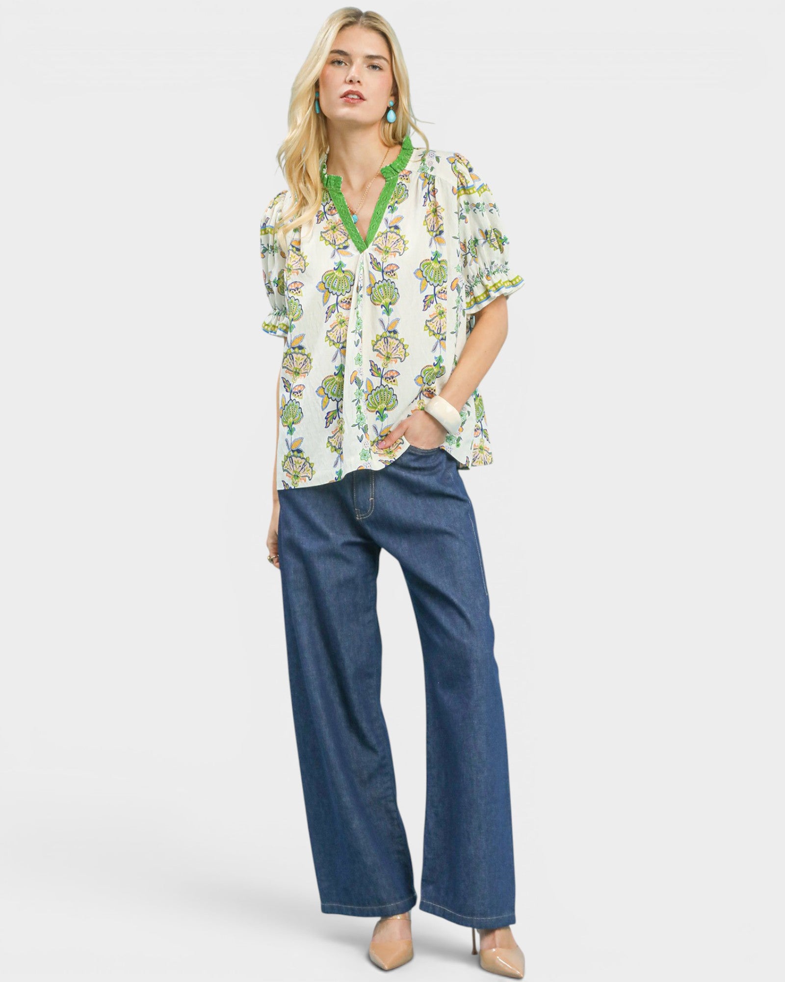 Woman wearing a floral blouse and blue jeans on a white background