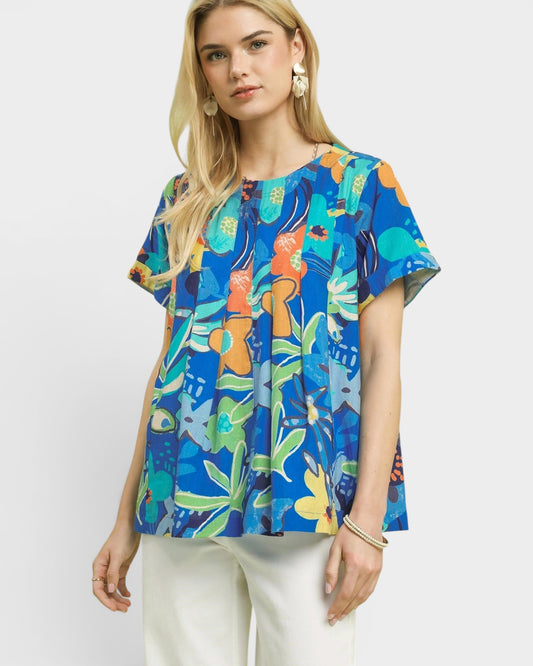 Woman wearing a colorful floral blouse against a white background