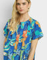 Woman wearing a colorful patterned dress against a plain background