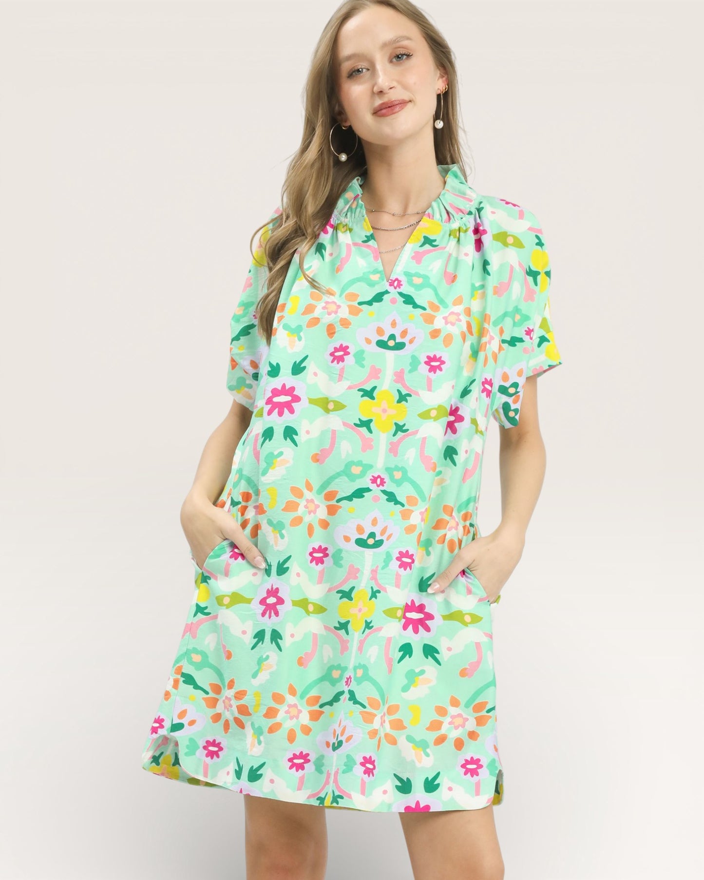 Woman wearing a colorful floral dress on a plain background