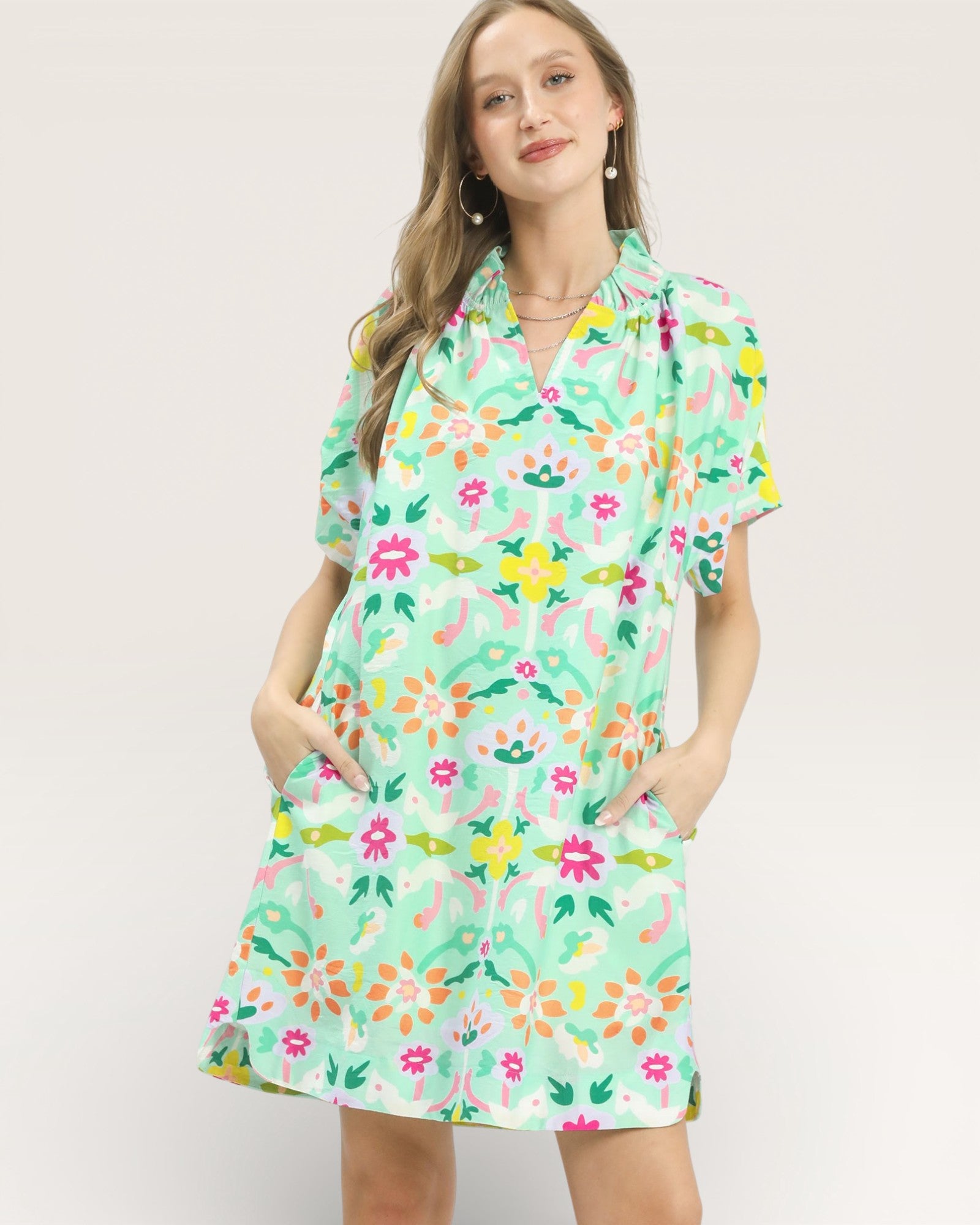 Woman wearing a colorful floral dress on a plain background