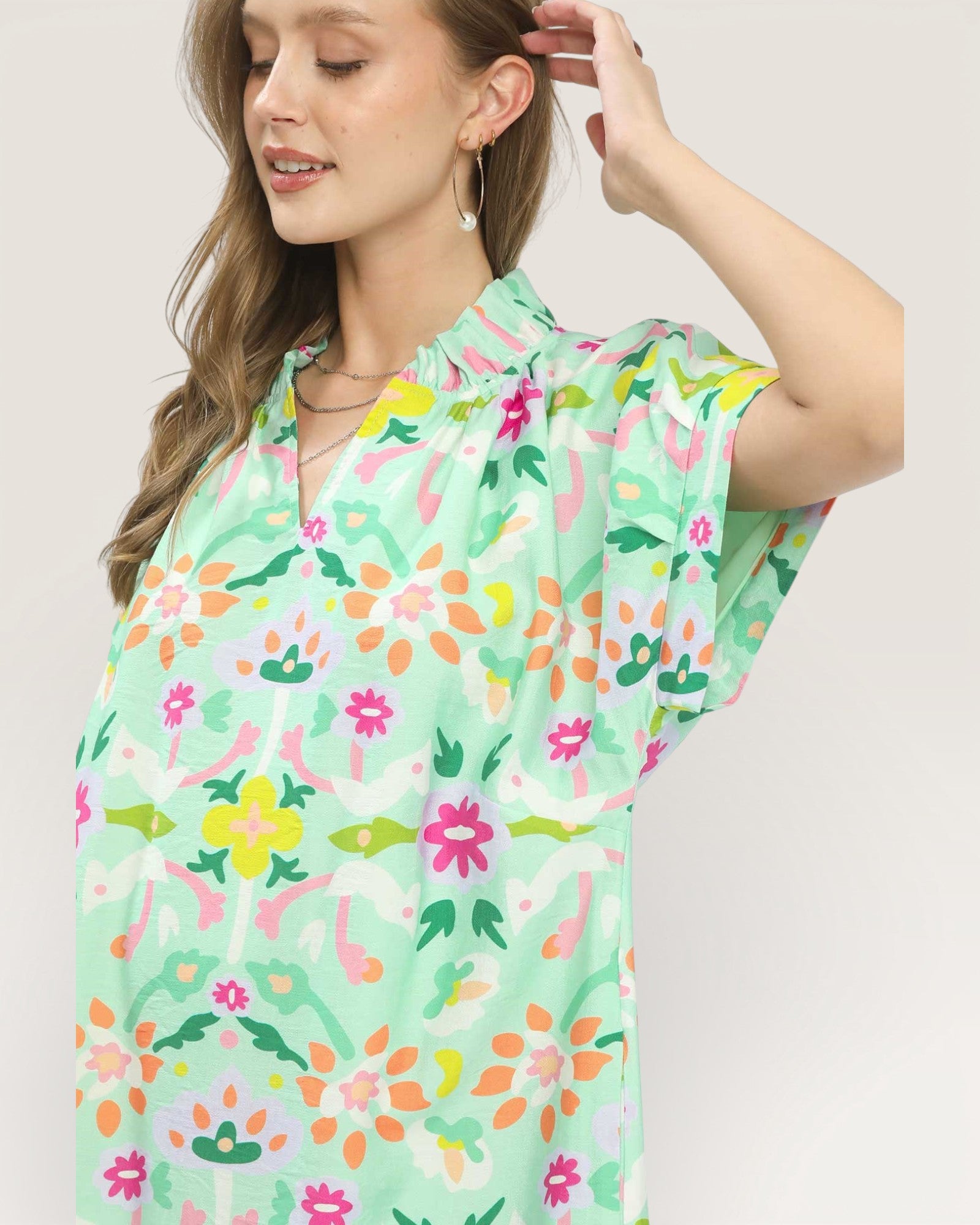 Woman wearing a colorful floral dress on a plain background