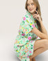 Woman wearing a colorful floral dress on a plain background