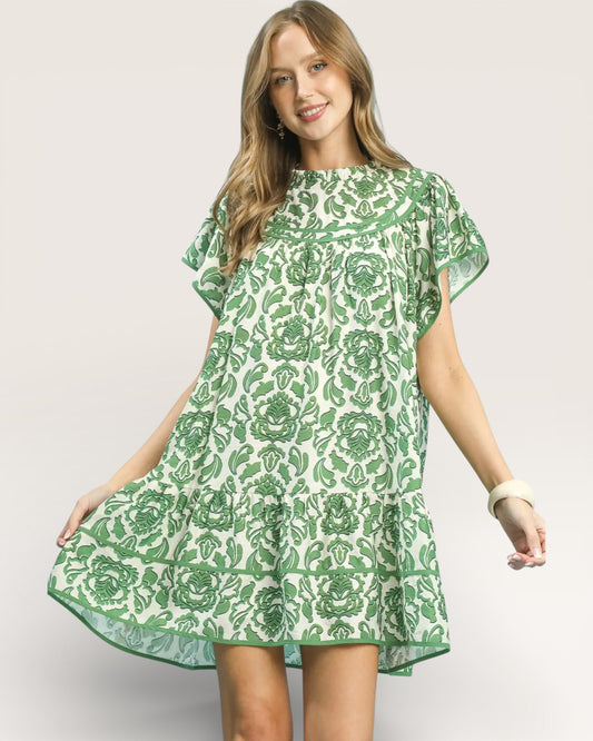 Woman wearing a green and white floral patterned dress on a plain background