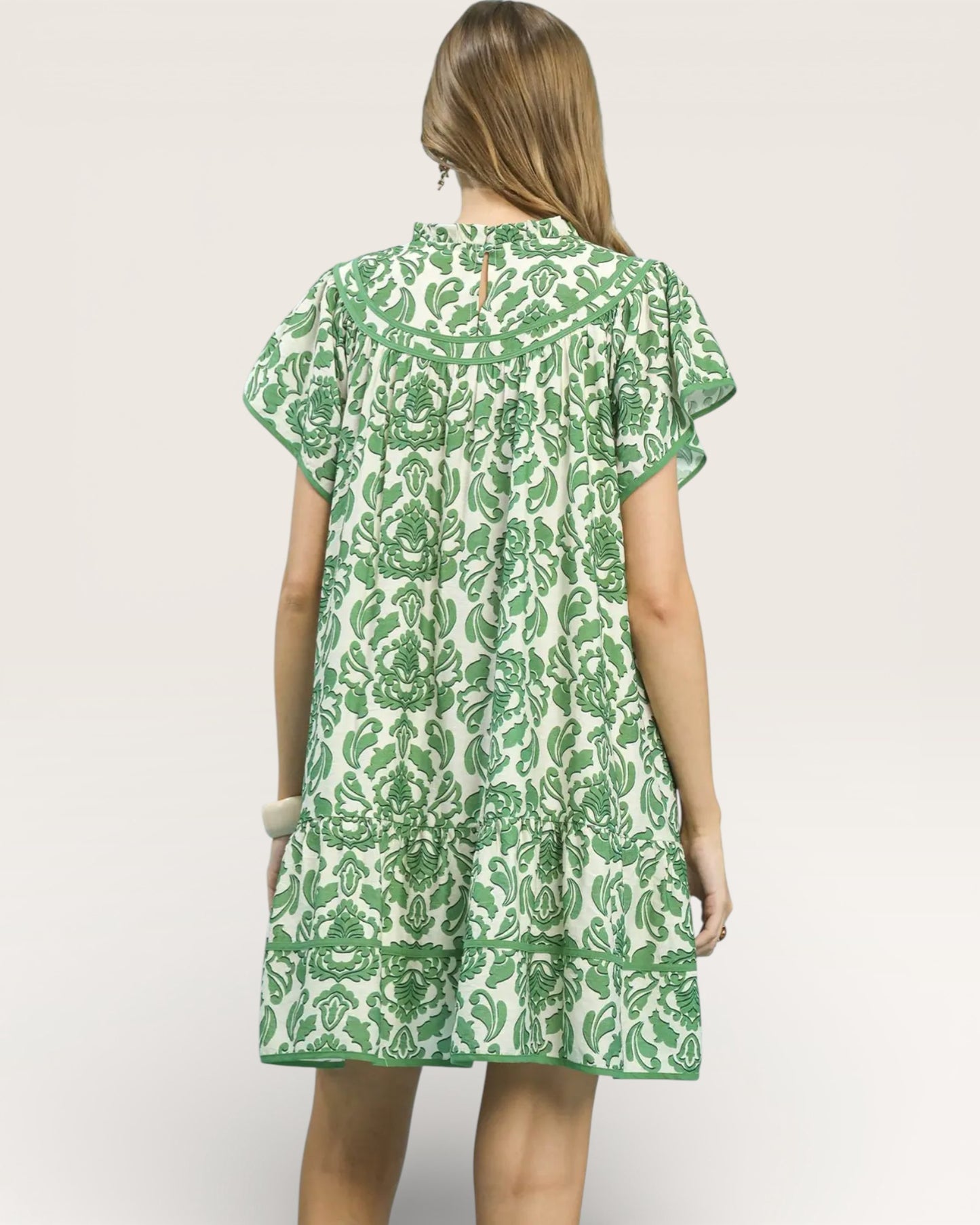 Woman wearing a green and white patterned dress on a plain background