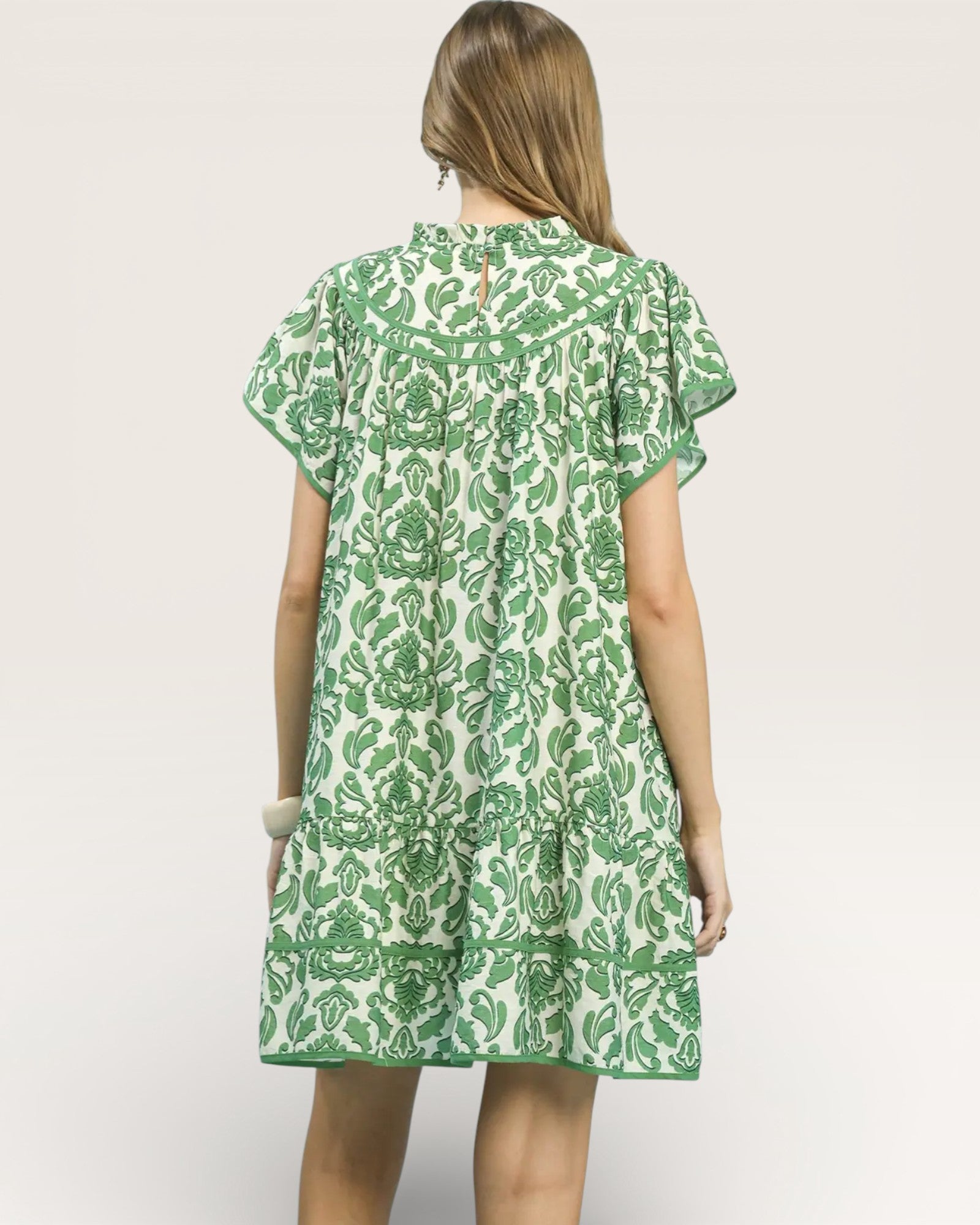 Woman wearing a green and white patterned dress on a plain background