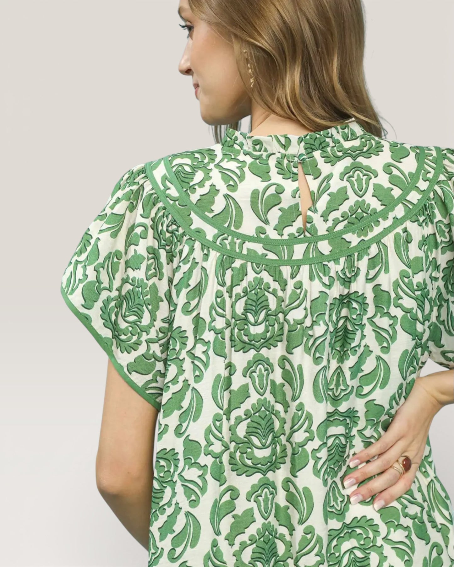 Green and white patterned dress worn by a person on a plain background