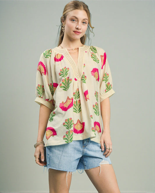 Woman wearing a floral blouse and denim shorts on a gray background