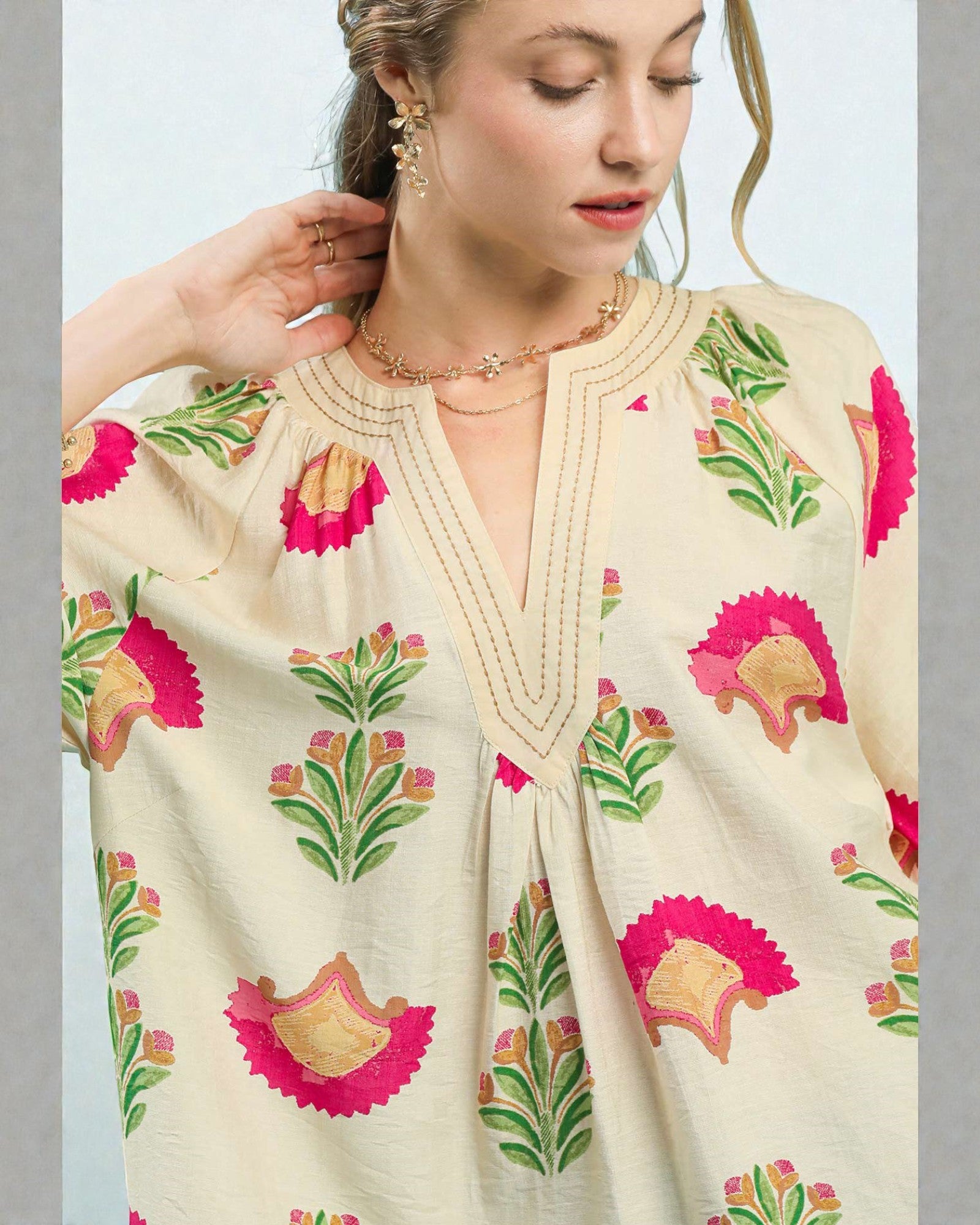 Woman wearing a cream-colored dress with floral patterns on a light gray background