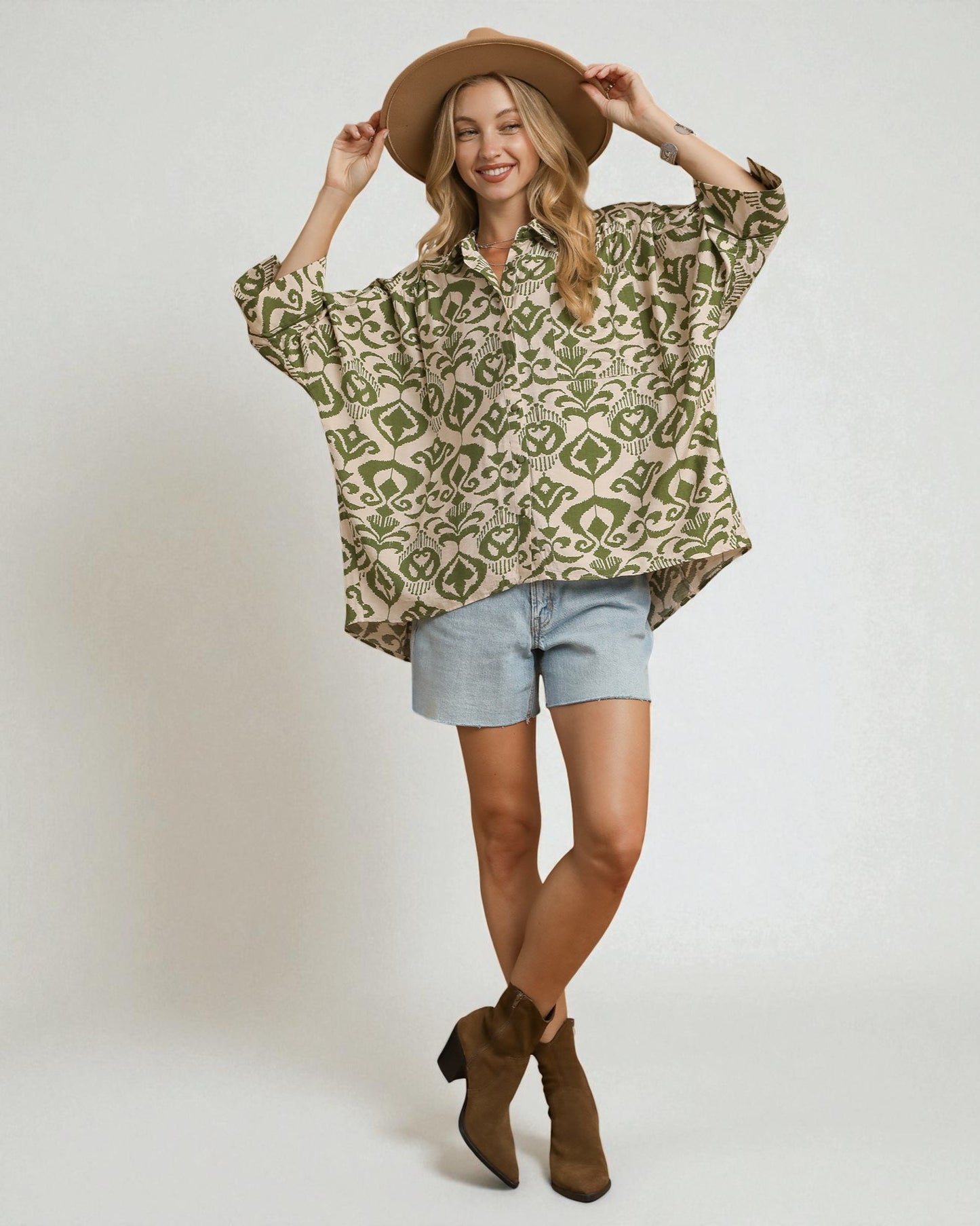 Woman wearing a patterned shirt, shorts, and boots on a plain background