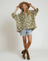 Woman wearing a patterned shirt, shorts, and boots on a plain background