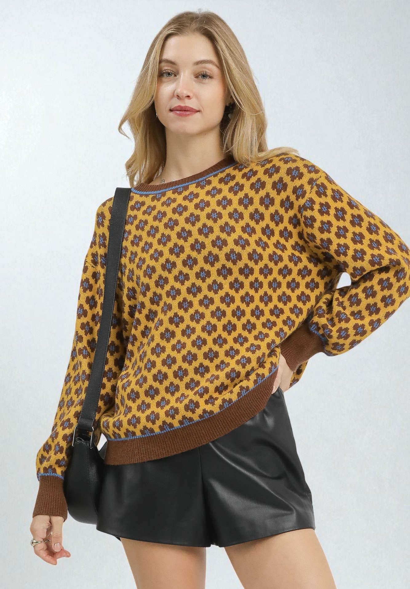 Woman wearing a patterned sweater and black leather shorts on a white background