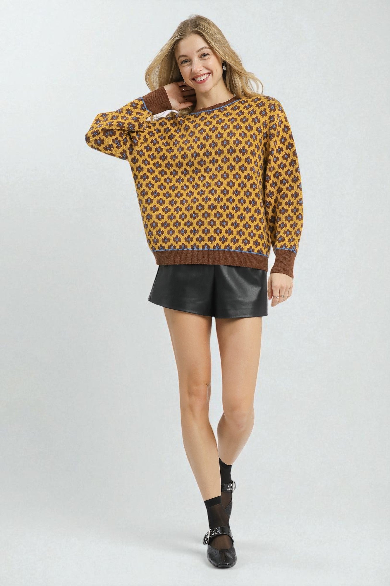 Woman wearing a patterned sweater and black shorts on a white background