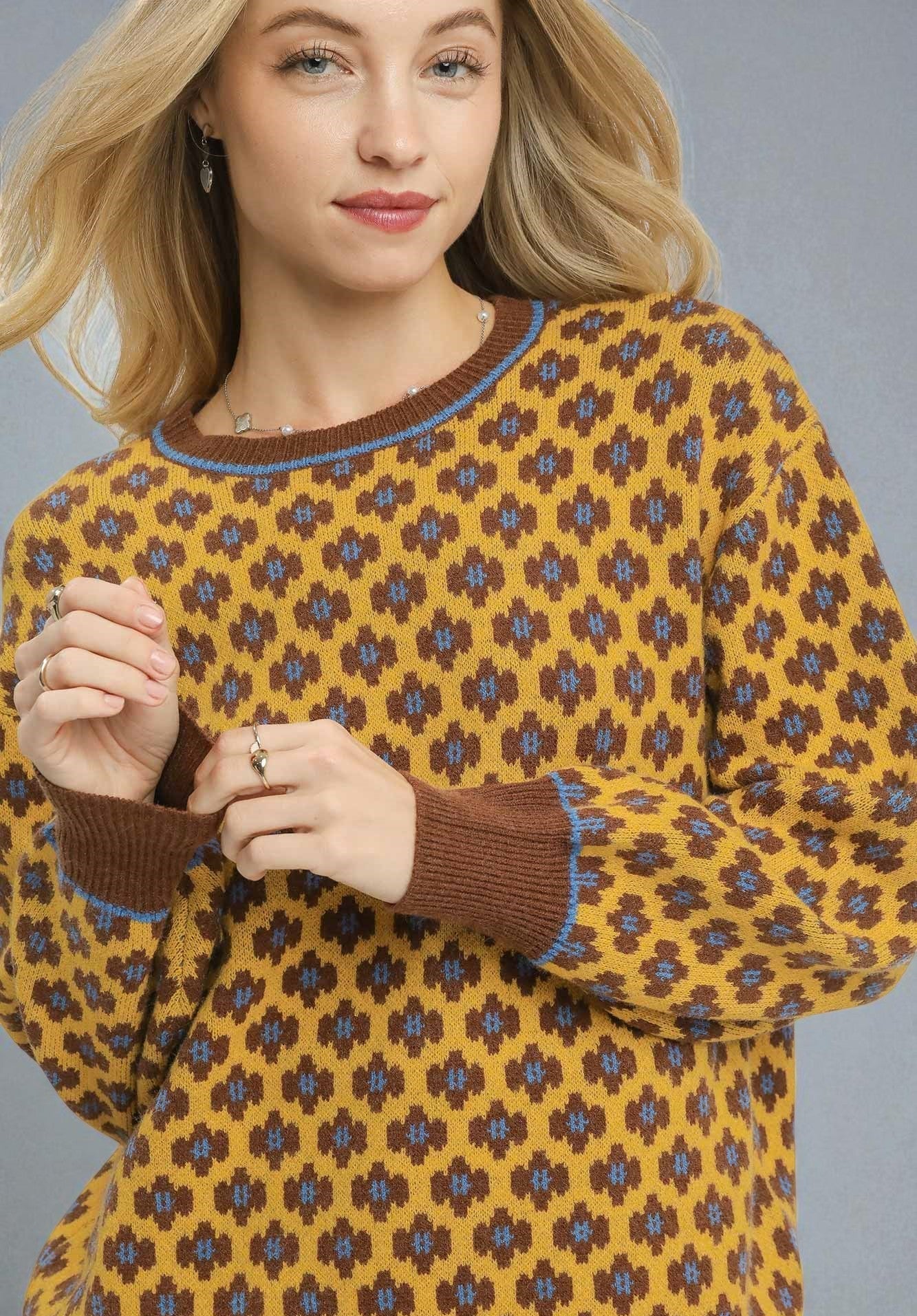 Woman wearing a patterned sweater with a yellow and brown design.