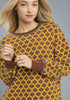 Woman wearing a patterned sweater with a yellow and brown design.