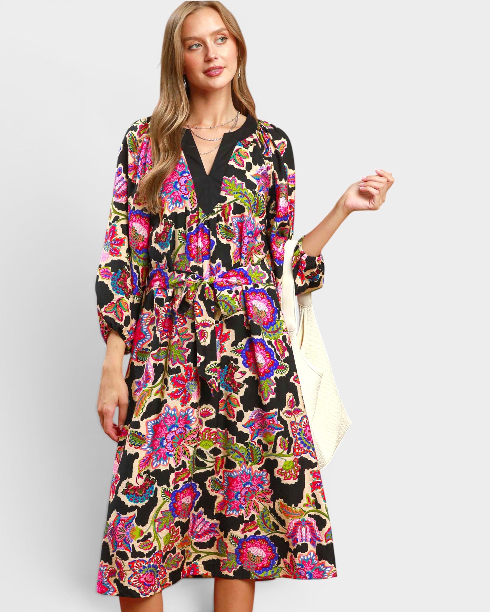 Woman wearing a colorful floral dress on a plain background