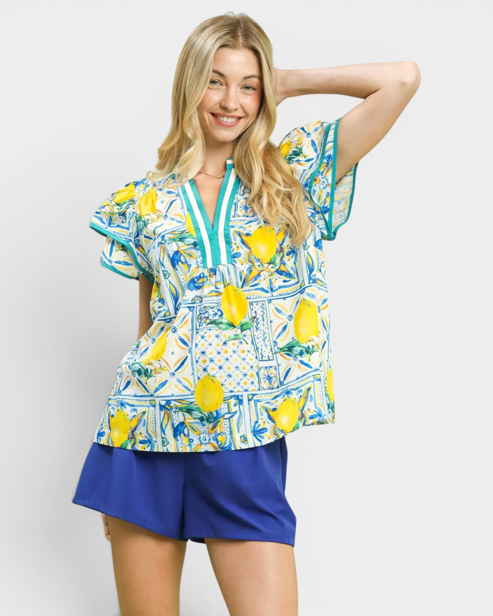 Woman wearing a colorful shirt with lemon pattern and blue shorts on a white background