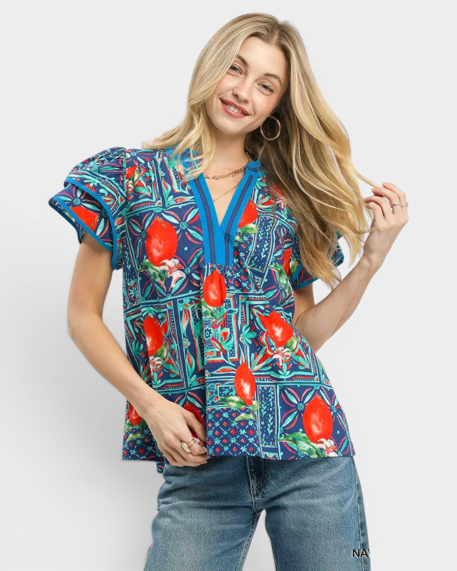 Woman wearing a colorful patterned blouse with red floral designs on a white background