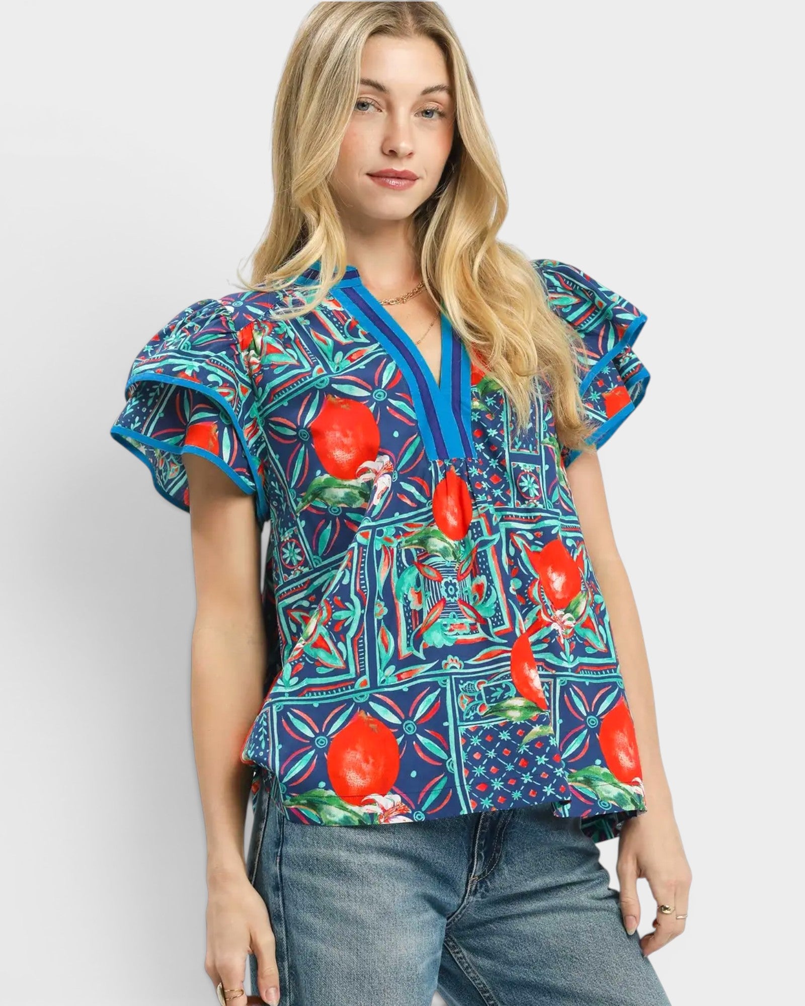 Woman wearing a colorful patterned blouse with ruffled sleeves on a white background