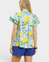 Woman wearing a colorful blouse with lemon pattern and blue shorts on a white background