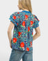 Person wearing a colorful floral shirt with red flowers on a white background
