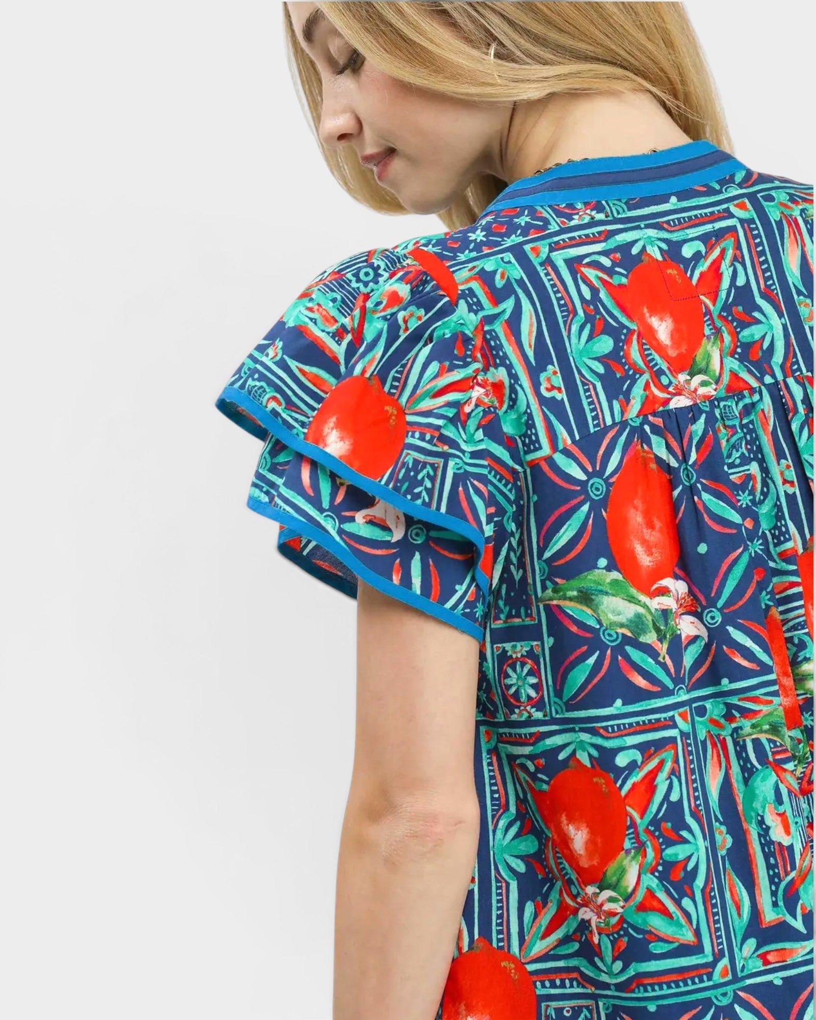 Woman wearing a colorful patterned shirt with red fruit design on a white background