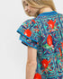 Woman wearing a colorful patterned shirt with red fruit design on a white background