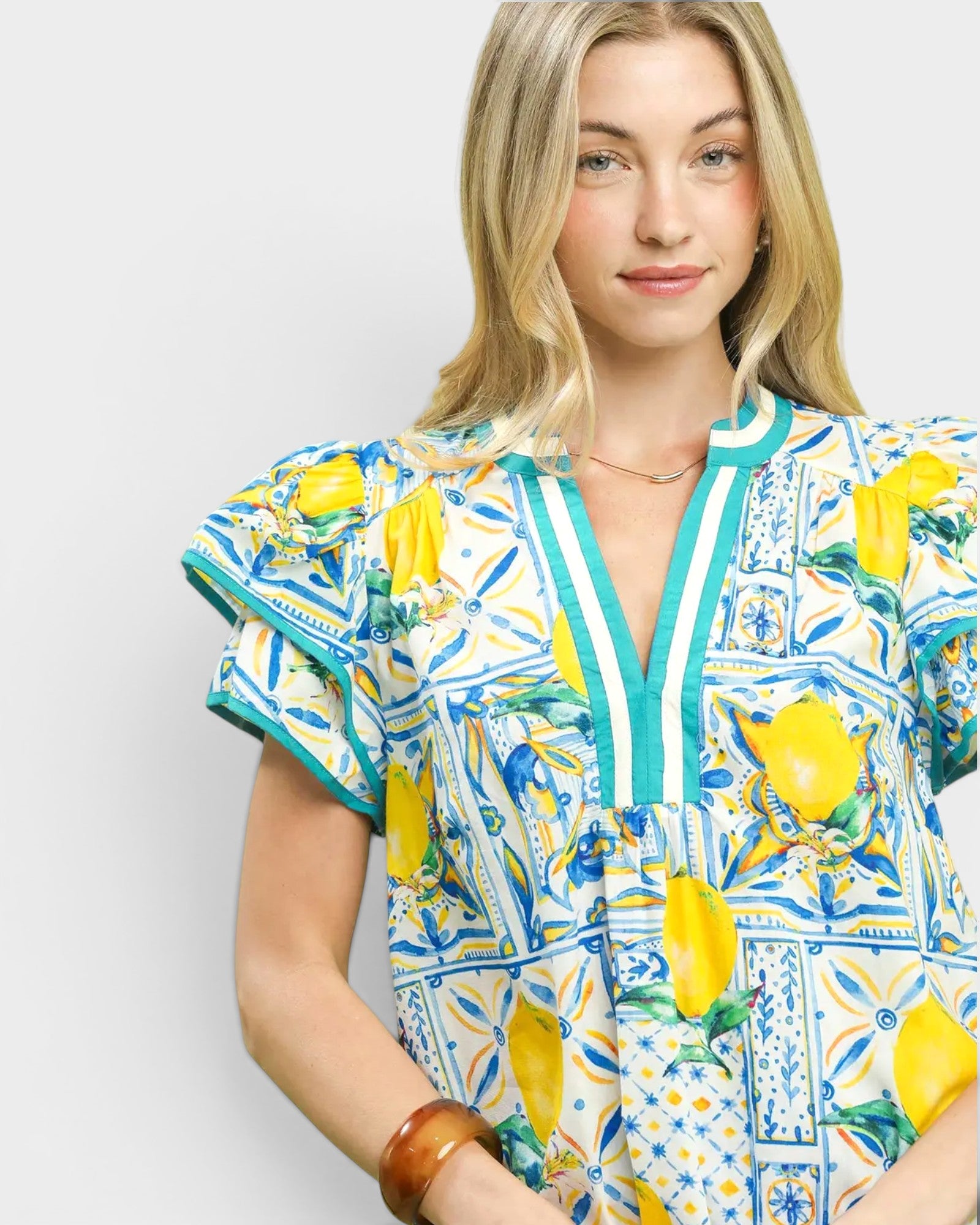 Woman wearing a colorful dress with lemon pattern on a plain background