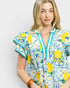 Woman wearing a colorful dress with lemon pattern on a plain background