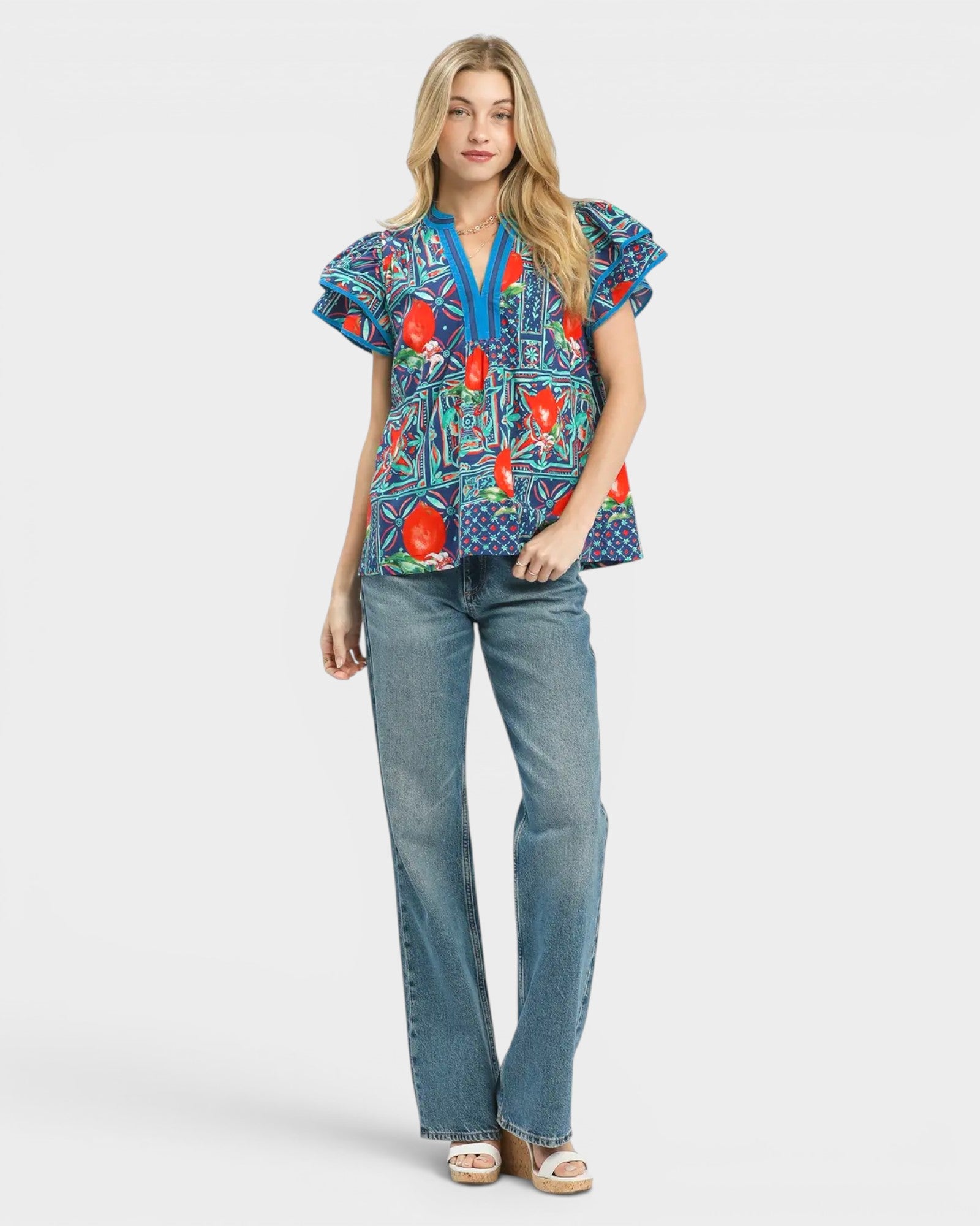 Woman wearing a colorful patterned blouse and blue jeans on a white background